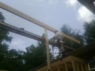 Carpenter setting a ridge beam over a new addition frame — Ice Dam Removal by Roofing Brothers in Bellerose
