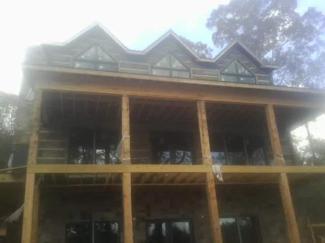 Dormers and porch framing on a large log home under construction — Roof Coating work by our crew in Bellerose