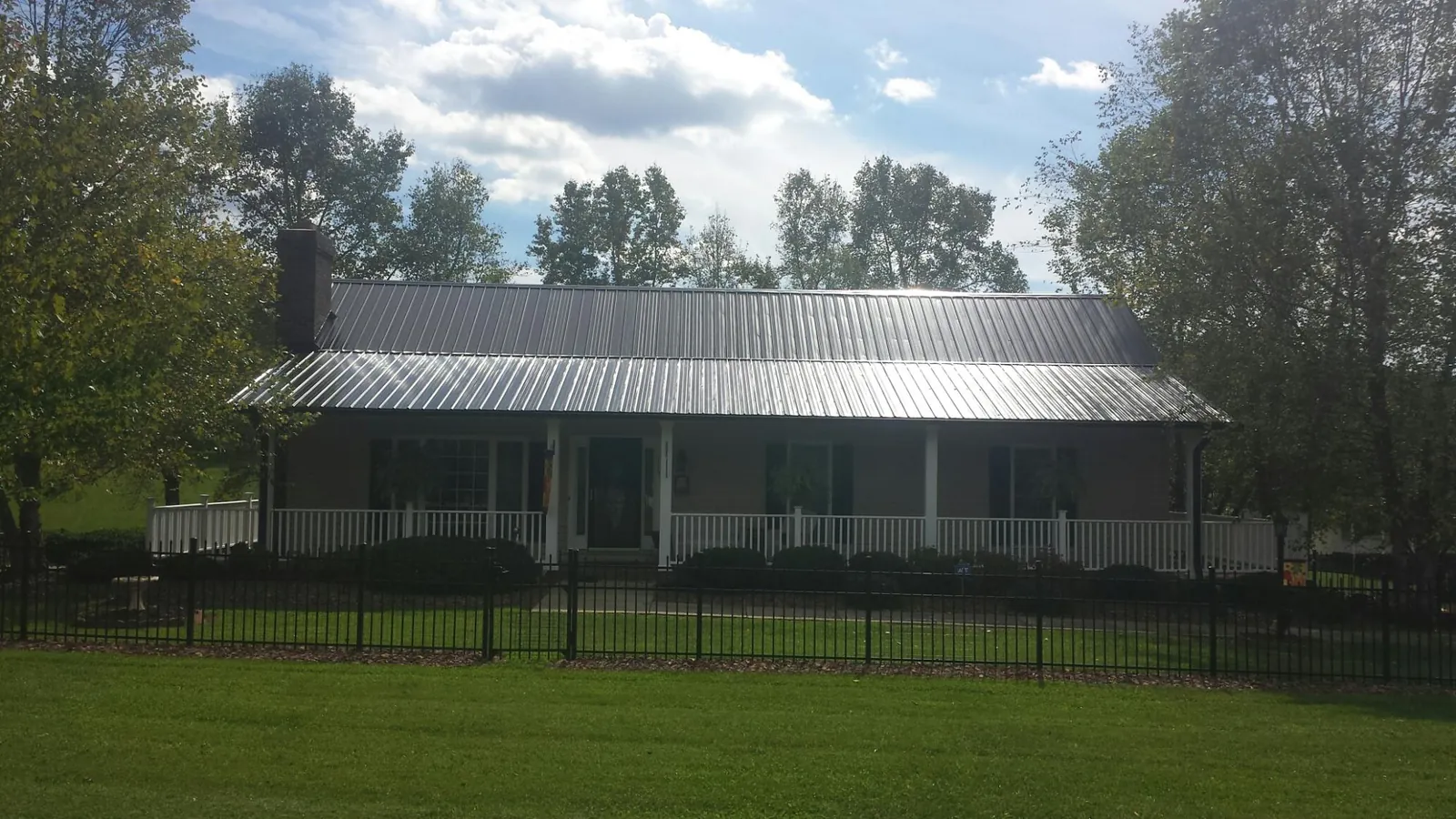 Gray metal roof on a brick ranch with a full width front porch — Gutter Guard Installation work by our crew in Bellerose